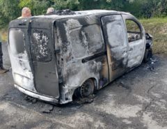 Burnt-out van in car park due to engine fire